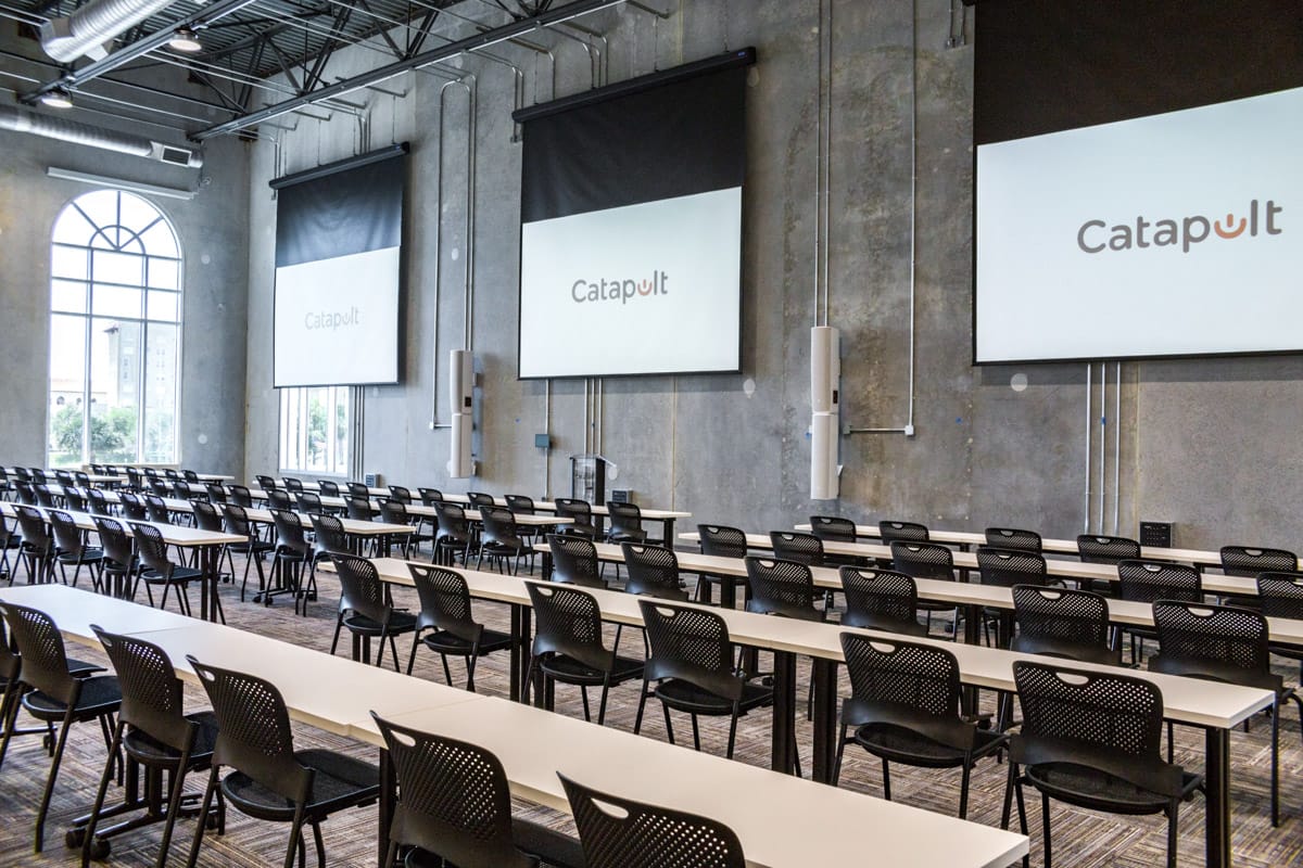 A large assembly room with multiple screens