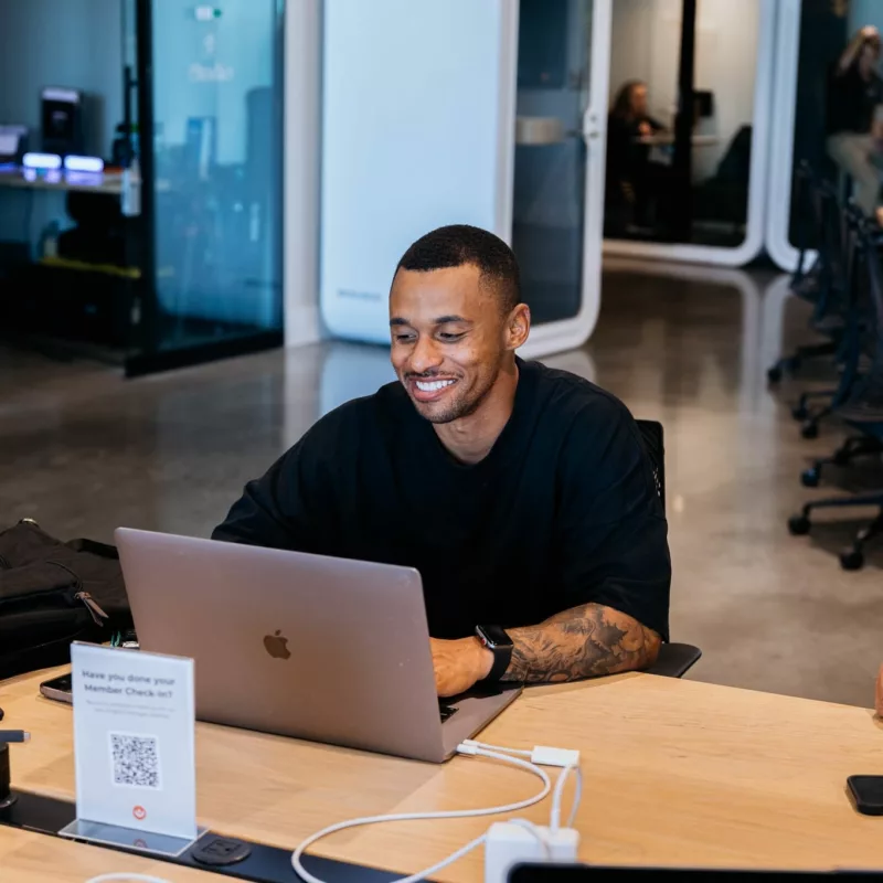 A Catapult workspace incubator member smiling at a laptop.